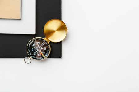 Black notepad for nautical notes and golden compass on a white tableの写真素材