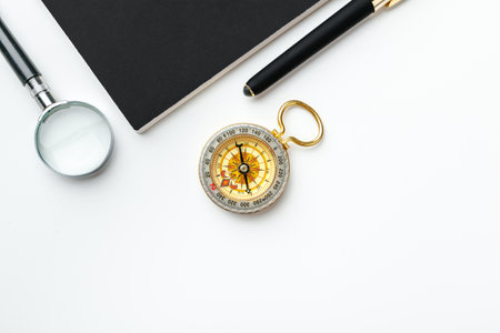 Golden compass with black notepad and pen close up on a table