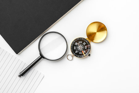 Golden compass with black notepad and pen close up on a tableの写真素材