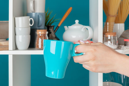 Hand of a woman taking kitchenware from a kitchen shelfの写真素材