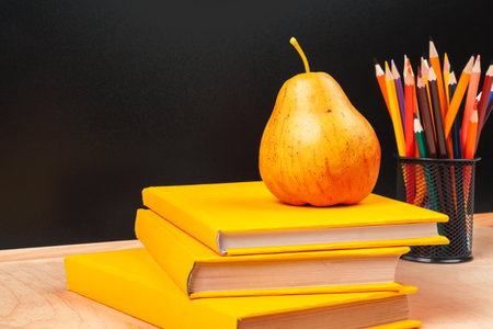 Different school supplies, books and pear on wooden tableの写真素材