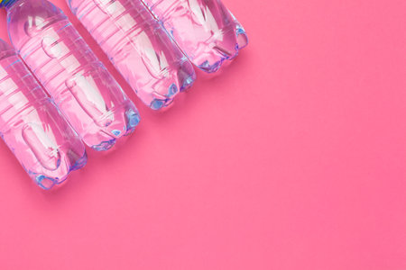 Plastic bottles with pure water on pink background top view space for textの写真素材