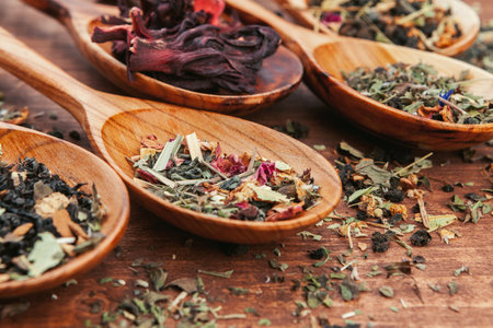 Black tea with herbs in wooden spoons on a wooden boardの写真素材