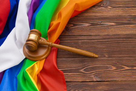 Woden judge mallet symbol of law and justice with lgbt flag in rainbow colours on wooden backgroundの写真素材