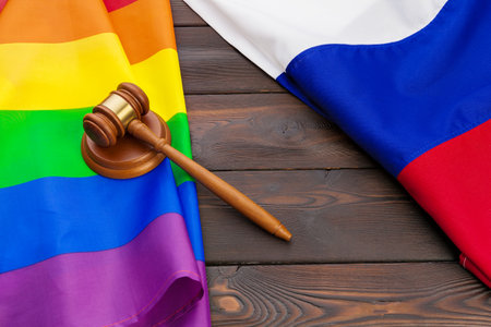 Woden judge mallet symbol of law and justice with lgbt flag in rainbow colours on wooden backgroundの写真素材