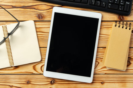 Top view of wooden table with white digital tablet with black screen on itの写真素材