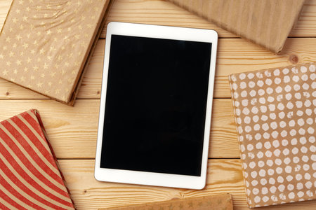 Top view of wooden table with white digital tablet with black screen on it