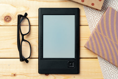 Portable e-book reader on wooden background top viewの写真素材