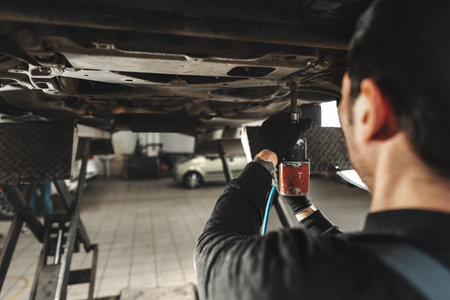 Workman mechanic working under car in auto repair shopの写真素材