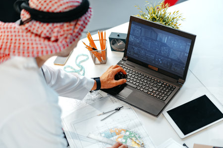 Young muslim businessman in traditional outfit working at the table in office