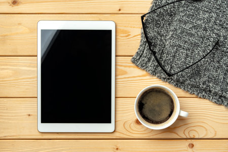 Top view of wooden table with white digital tablet with black screen on itの写真素材