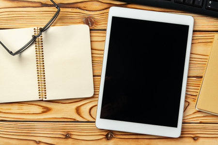 Top view of wooden table with white digital tablet with black screen on itの写真素材