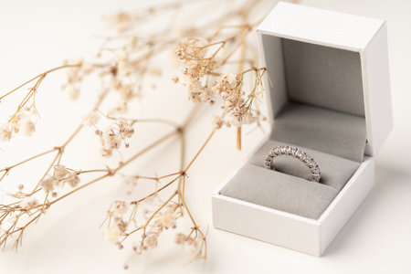 Golden diamond ring in the box with white flower background