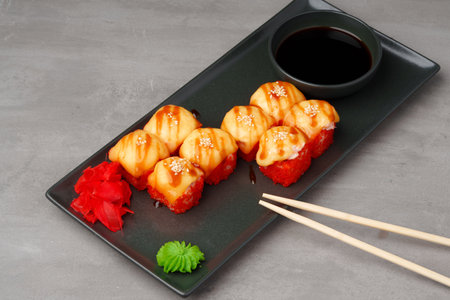 Baked sushi rolls on black plate on gray backgroundの写真素材
