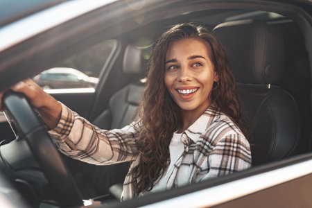 Portrait of a beautiful smiling woman in a car looking out of the window