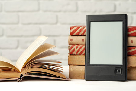 E-book reader device on background of paper booksの写真素材