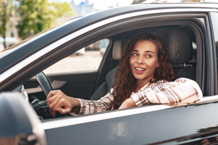 Young smiling woman driving a car in the city