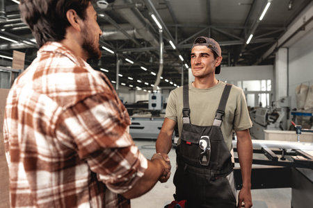 Two men shaking hands on background of workshopの写真素材