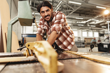 Young carpenter working on woodworking machines in the furniture factoryの写真素材