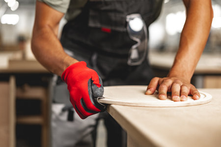 Close-up of carpenters hands working with wood piece in a workshopの写真素材