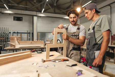 Two young men carpenters making furniture in warehouse of wood factoryの写真素材