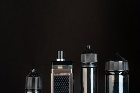 Vape and vape liquid bottles against black background