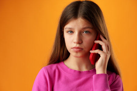 Teen girl over yellow wall talking on smartphone