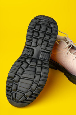 Beige sport running shoes on yellow studio background