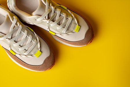 Beige sport running shoes on yellow studio background