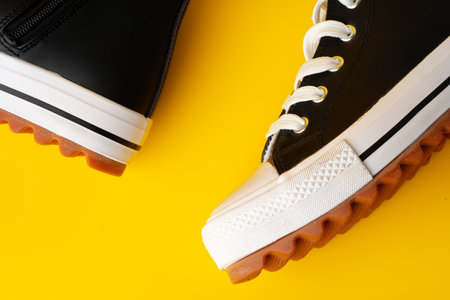 New black and white canvas sneakers on yellow background