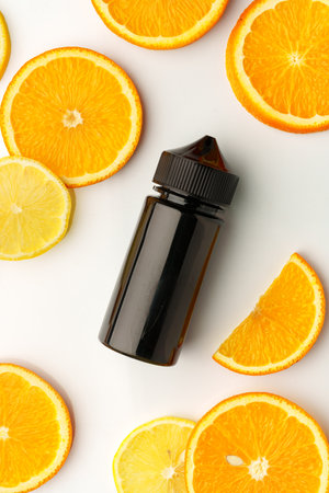 Vape smoking liquid with orange flavor on white background with orange piecesの写真素材
