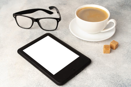 E-book reader, cup of coffee and glasses on gray surfaceの写真素材