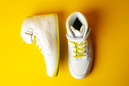 White sneakers with yellow neon laces on yellow backgroundの写真素材
