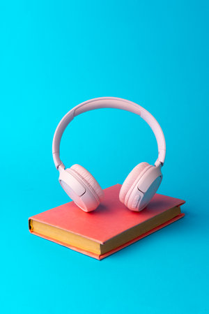 Pink headphones on a book on blue backgroundの写真素材