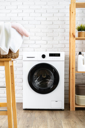 Laundry room with washing machine and basket with laundryの写真素材