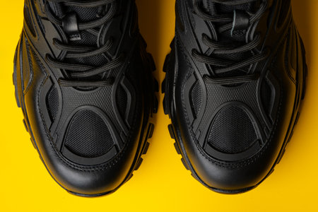 Black new sport sneakers on yellow backgroundの写真素材