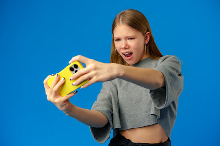 Stylish teen girl using smartphone over blue backgroundの写真素材