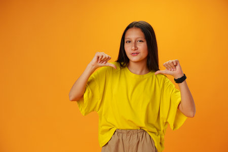 Teenager girl over yellow background points finger at herselfの写真素材
