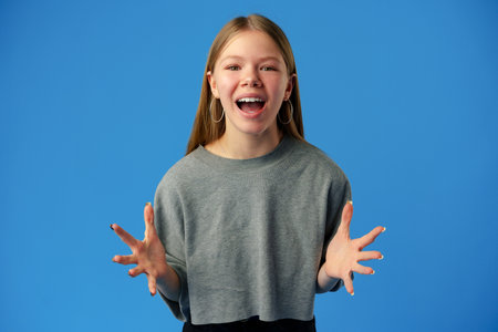 Surprised amazed teen girl against blue background in studio