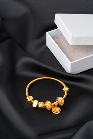 Golden bracelet with jewelry box on black silk backgroundの写真素材