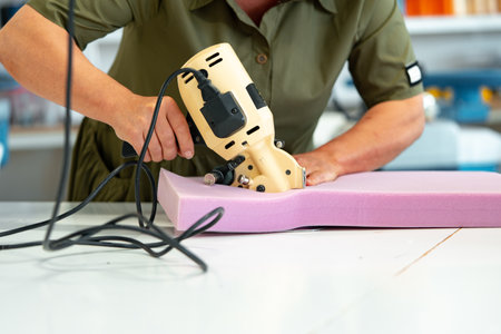 Hands of a furniture master cut a piece of foam with foam cutting machineの写真素材