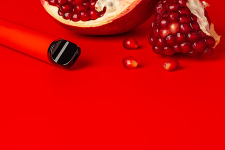 Electronic cigarette with pomegranate flavor on red backgroundの写真素材