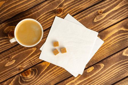 Top view of coffee cup and paper napkins on brown wooden background