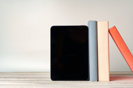 Digital tablet with a stack of books on gray backgroundの写真素材