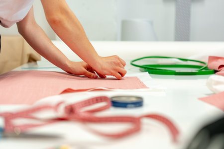 Seamstress working with fabric in sewing factory close up
