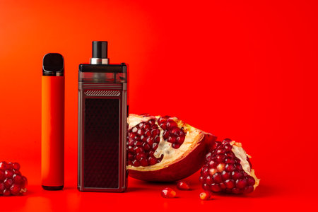 Electronic cigarette with pomegranate flavor on red backgroundの写真素材