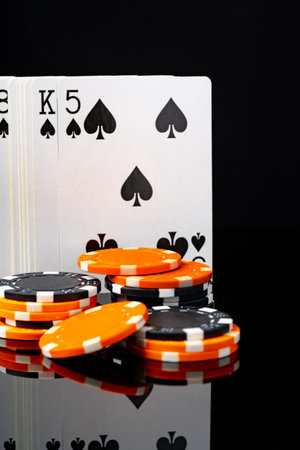 Playing cards and poker chips on black background