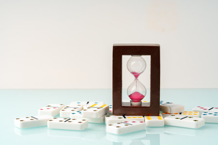Hourglass and domino tiles on blue background. Time limit conceptの写真素材