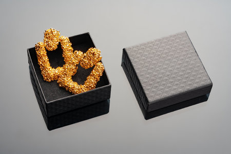 Golden earrings on black background with reflection