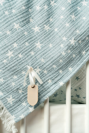 Cotton baby blanket with paper tag hanging from baby bedの写真素材